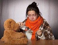 Mujer con gripe y oso de peluche